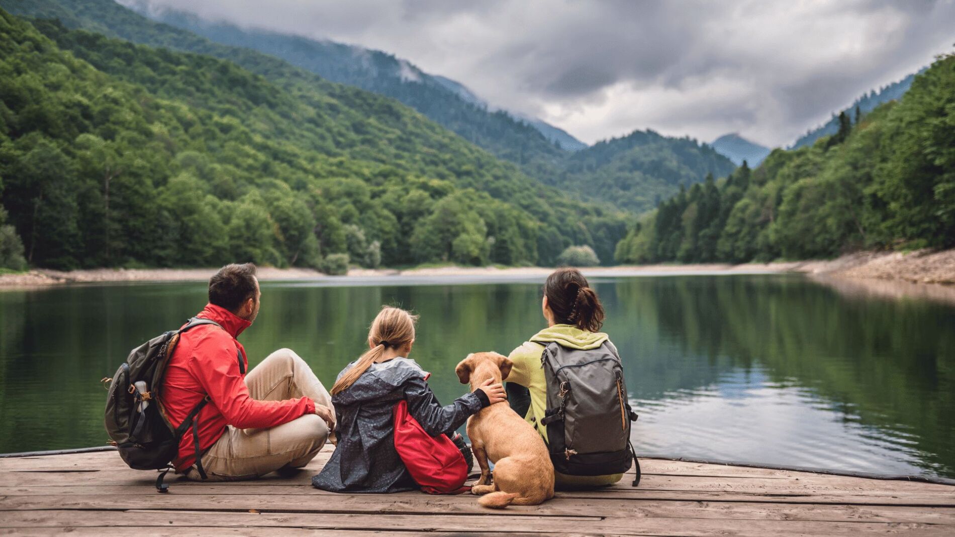 family and dog sitting by the lake